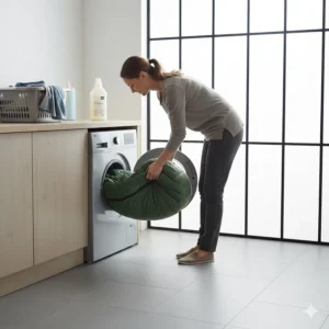 A synthetic camping sleeping bag being placed into a domestic washing machine, demonstrating easy care and maintenance.