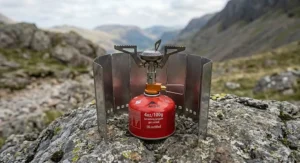 A folding foil windshield protecting an ultralight titanium backpacking stove from the wind during a wild camping trip in the Lake District.