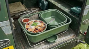 A small portable bbq used for outdoor catering, showing a fruit crumble being kept warm in an enamel dish.