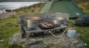 A two-burner gas camping stove with a grill, suitable for family camping trips in the UK.