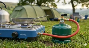 A stainless steel whistling kettle boiling water on a high-power camping stove hob for a family brew.