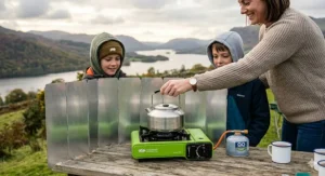 A lightweight folding camping stove wind shield set up on a picnic bench.