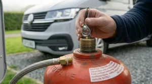 An inspector using a magnifying glass to check the rubber seal and thread of a camping gas cylinder.