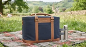 A structured navy and tan cool bag sitting upright in a field.