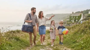 A family walking through a coastal path carrying their large cool bag on a day trip.