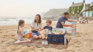 A family using a large cool bag while enjoying a day out at a scenic British beach.
