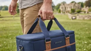 Close-up of a person carrying a large, high-quality cool bag by its durable padded handles.