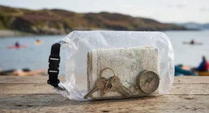 Bright yellow dry bag with a clear window showing small items inside like a map and car keys.