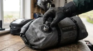 Finger opening the air compression valve on a tight motorcycle dry bag to reduce volume.